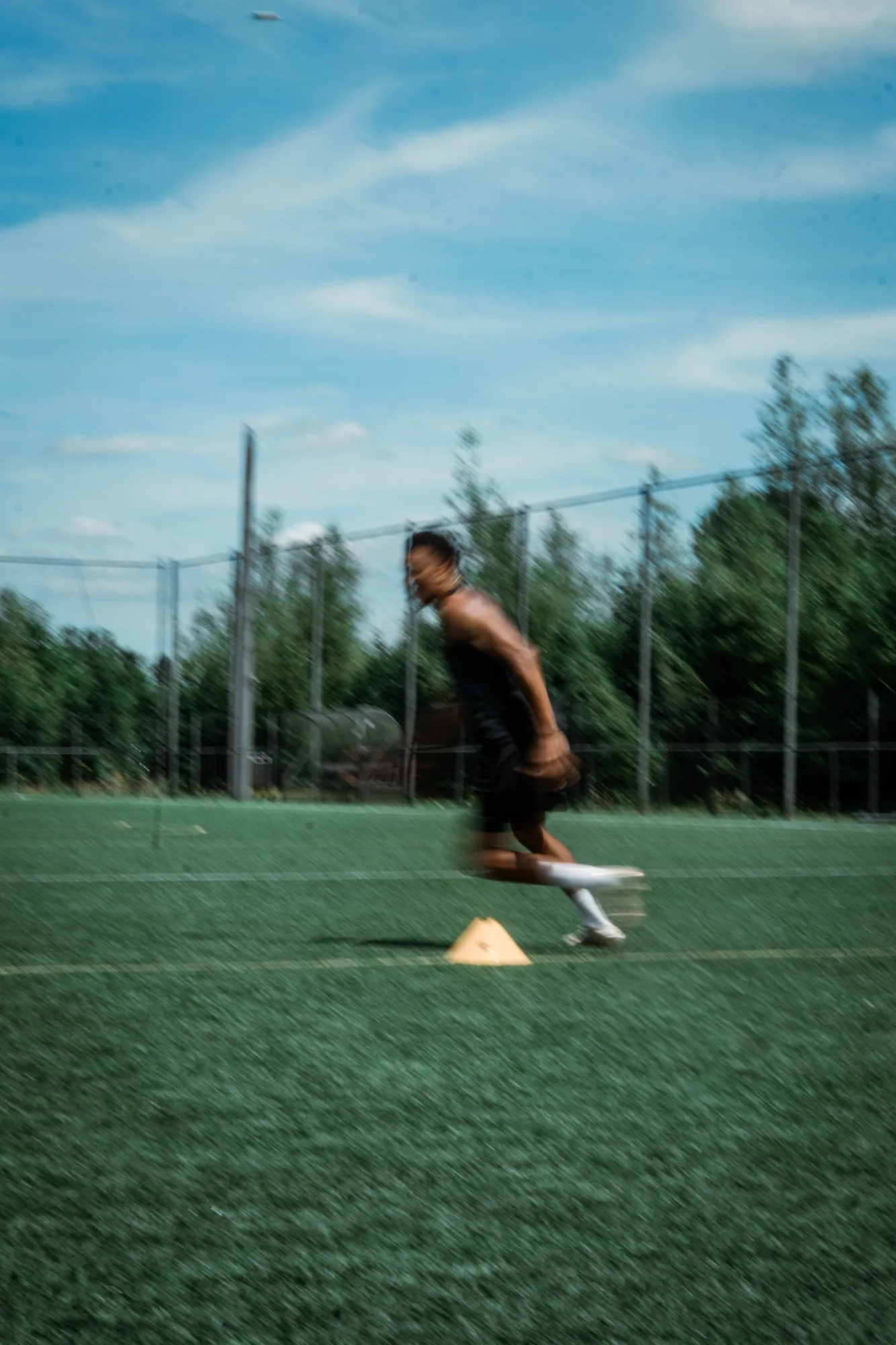 Joueur professionnel en plein sprint lors d'un exercice d'agilité sur plots
